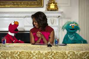 First Lady Michelle Obama, with Sesame Street Muppets Elmo and Rosita, makes a "Let's Move!" announcement about marketing healthier foods to children, in the State Dining Room of the White House. (Official White House Photo by Lawrence Jackson)