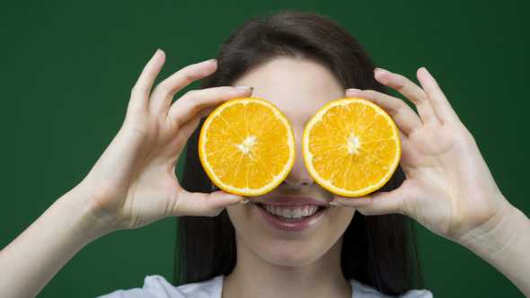 young lady goofing around with orange slices for eyes