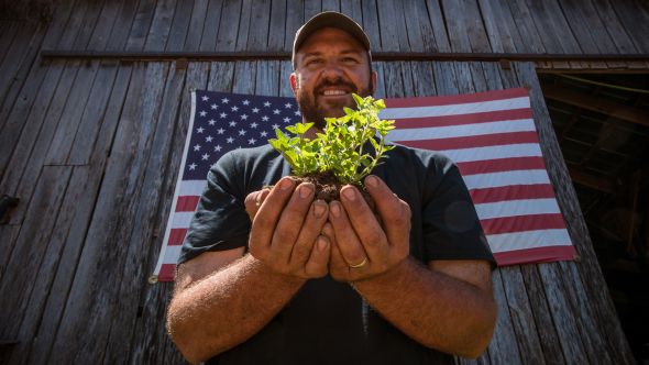 U.S. Marine Corps veteran Calvin Riggleman holds an oregano seedling and soil on Bigg Riggs farm in Hampshire County, WV. Riggleman served in Iraq and serves his community farm fresh organic produce, and food products made by the Bigg Riggs Farm team. (Photo credit: USDA)